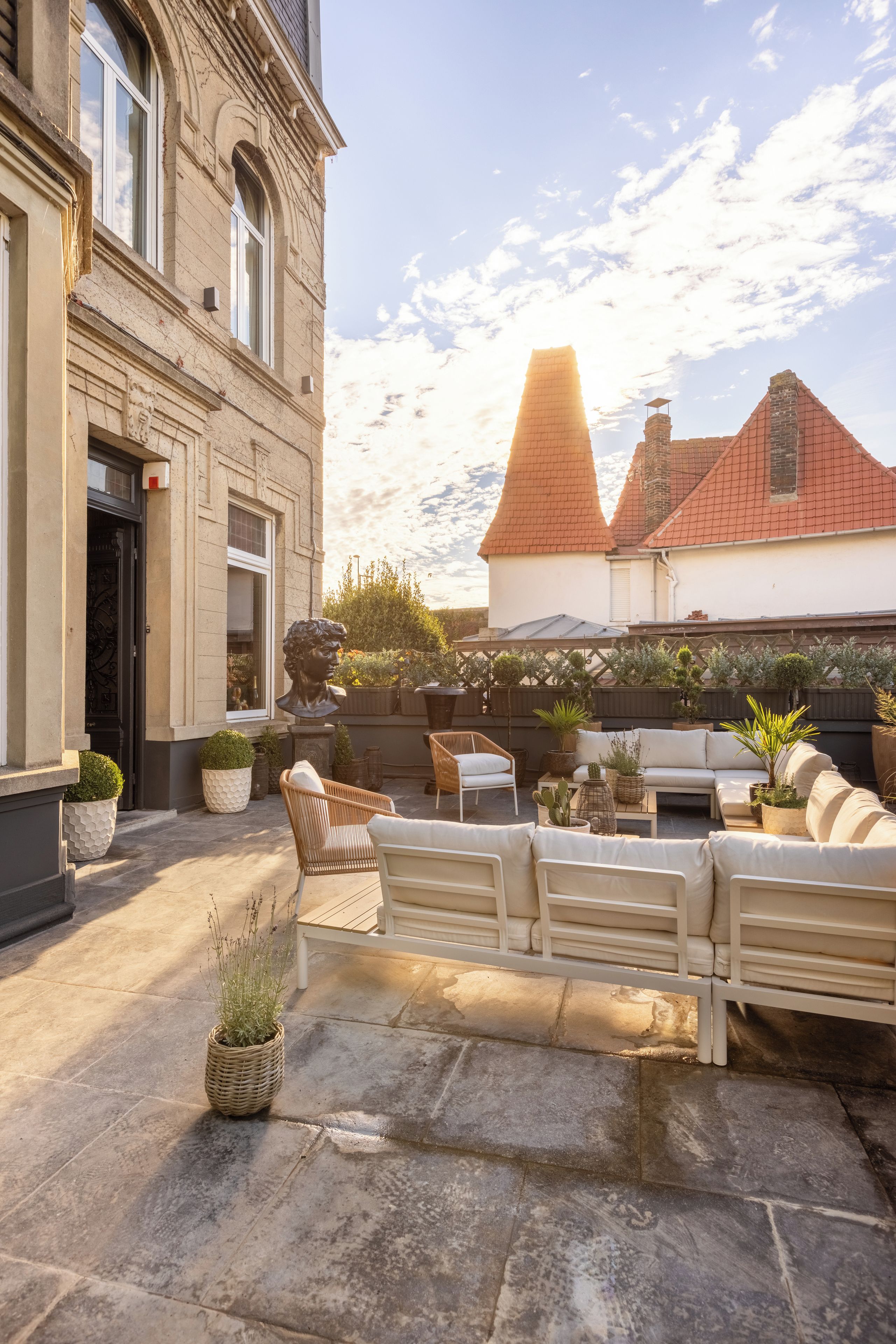 Een binnenplaats met terras, een standbeeld en een gebouw in klassieke stijl.