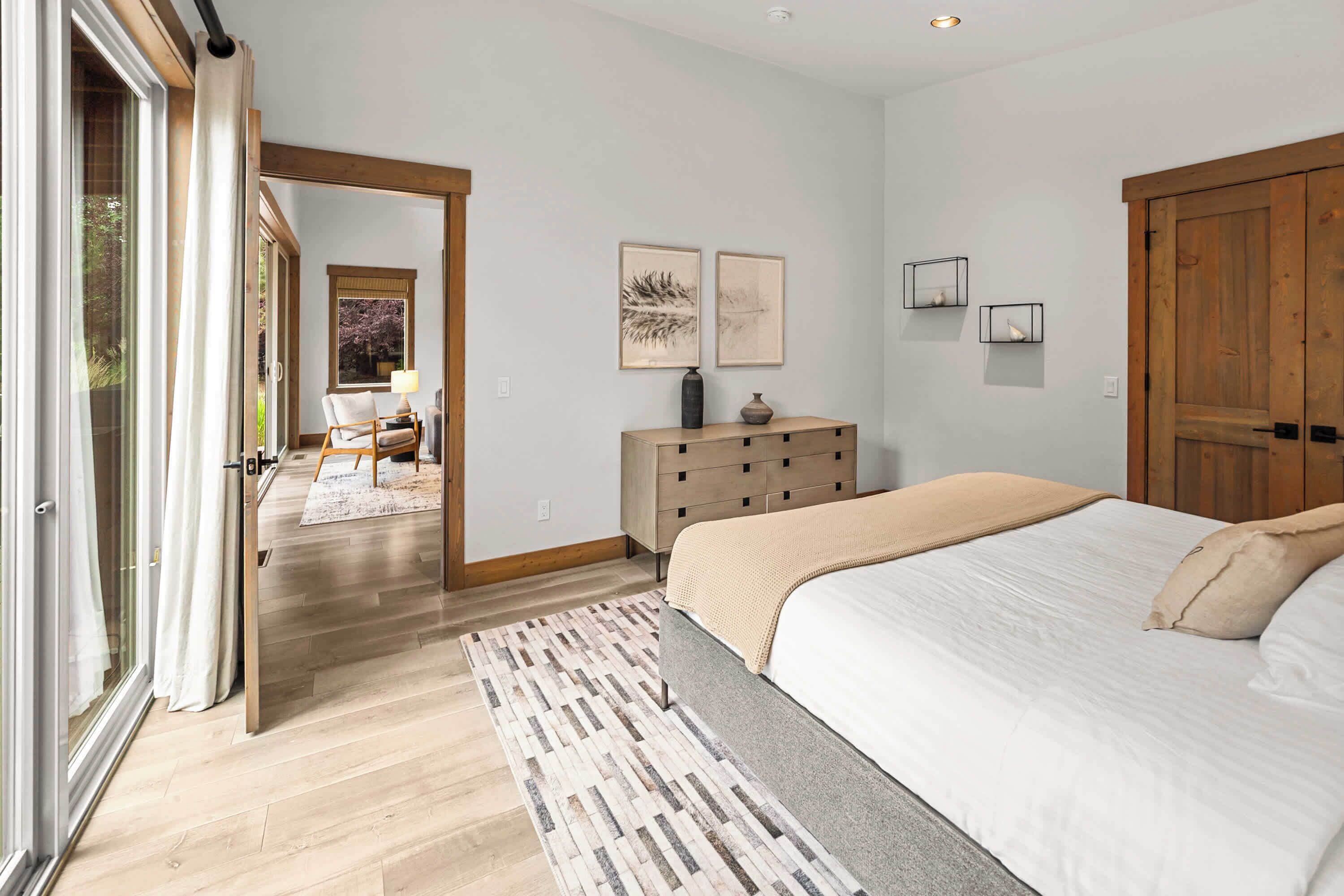 A bedroom with a bed, a dresser, a mirror, and artwork on the wall.