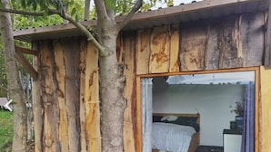 A rustic wooden cabin with a single window and a visible bed inside. - Tiny House with Sauna and Hot Tub: Nature, Relaxation, Peace, Wellness  (Schmölln)