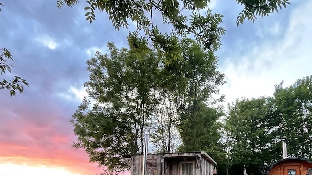 A rustic cabin with a wooden deck, a bench, and a small shed. - Tiny House with Sauna and Hot Tub: Nature, Relaxation, Peace, Wellness  (Schmölln)