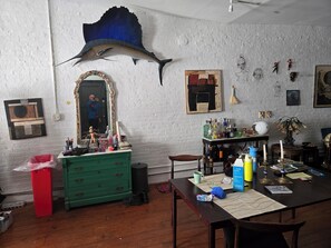 A room with a large mirror, a wooden table with various items, a green dresser, and a blue fish mounted on the wall. - Hosted Loft in SoHo ! (New York)