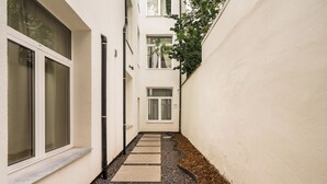 A narrow pathway leading to a door, flanked by a white wall and a window on the left. - New apartment in downtown Antwerp for 6 people (Antwerpen)