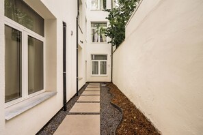 A narrow pathway leading to a door, flanked by a white wall and a window on the left. - New apartment in downtown Antwerp for 6 people (Antwerpen)