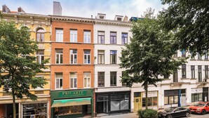 A row of multi-story buildings with various storefronts, including a visible shop named 'PRO ARTE' with a green awning. - New apartment in downtown Antwerp for 6 people (Antwerpen)