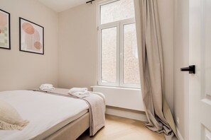 A bedroom with a bed, a window with curtains, and two framed pictures on the wall. - New apartment in downtown Antwerp for 6 people (Antwerpen)
