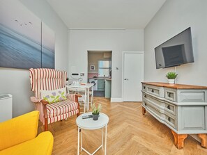 A modern living room with a striped armchair, a yellow sofa, a small white table with a plant, and a grey cabinet with drawers. - No.3 Dunluce Apartments - UK52009 (Portrush)