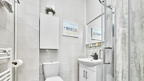 Een moderne badkamer met toilet, wastafel en douche.