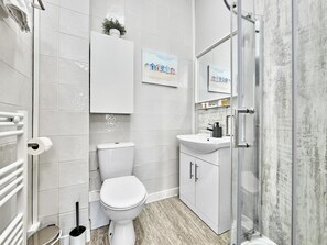 A modern bathroom with a toilet, sink, and shower. - No.3 Dunluce Apartments - UK52009 (Portrush)