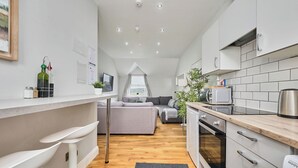 Eine moderne Küche mit Essbereich, einer Couch und Blick ins Freie.