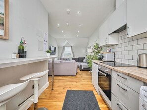 Eine moderne Küche mit Essbereich, einer Couch und Blick ins Freie.
