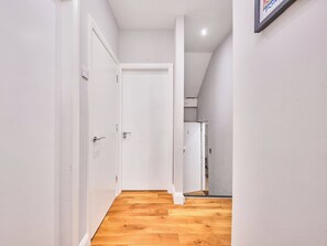 Ein Korridor mit Holzboden, weißen Wänden und Türen zu weiteren Räumen.