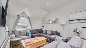 Ein modernes Wohnzimmer mit einem grauen Sofa, einem kleinen runden Tisch und einer Lampe.