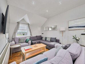 Ein modernes Wohnzimmer mit einem grauen Sofa, einem kleinen runden Tisch und einer Lampe.