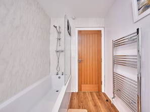 Ein Badezimmer mit einer Badewanne, einer Holztür und einem Handtuchhalter.
