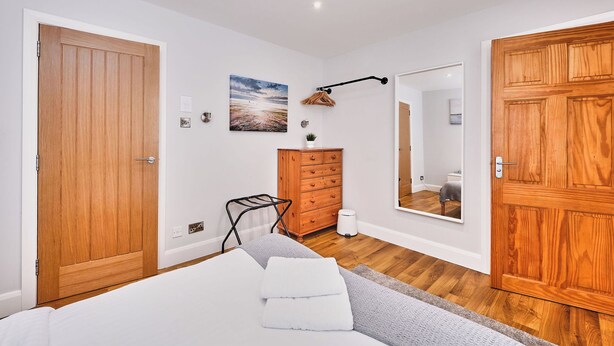 Ein Schlafzimmer mit Bett, Holzschrank, Kommode und Spiegel.
