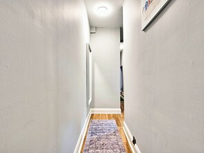 A narrow hallway with white walls, a wooden floor, and a patterned rug. - No.1 Dunluce Green Apartments - UK52014 (Portrush)