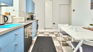 Een kleine keuken met een vaatwasser, een waterkoker en een koffiezetapparaat op het aanrecht.