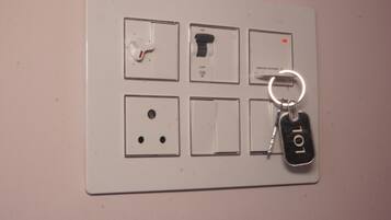 Un panel eléctrico empotrado en la pared con varios interruptores y un llavero con la inscripción 'LOL'.