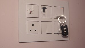 A wall-mounted electrical panel with multiple switches and a keychain with 'LOL' attached. - Illayanar Home Stay (Tiruvannamalai)