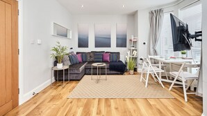 A modern living room with a sofa, a coffee table, a TV, and a desk with chairs. - No.2 Princess Red Apartments - UK52041 (Portrush)