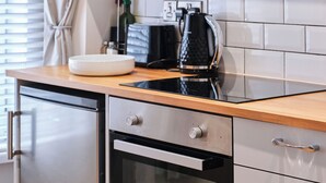 A modern kitchen with a black induction cooktop, a white bowl, and a coffee maker. - No.2 Princess Red Apartments - UK52041 (Portrush)
