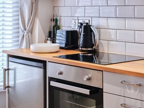 Eine moderne Küche mit einer schwarzen Induktionskochplatte, einer weißen Schüssel und einer Kaffeemaschine.