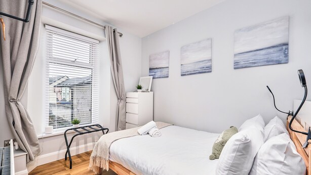 A bedroom with a bed, a dresser, a window with curtains, and wall art. - No.2 Princess Red Apartments - UK52041 (Portrush)