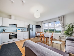 A modern kitchen with white cabinets, a built-in oven, and a stainless steel refrigerator. - No.6 Dunluce Park Apartments - UK52047 (Portrush)