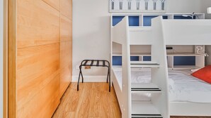 A bunk bed room with a wooden wardrobe, a small table, and a painting on the wall. - No.6 Dunluce Park Apartments - UK52047 (Portrush)