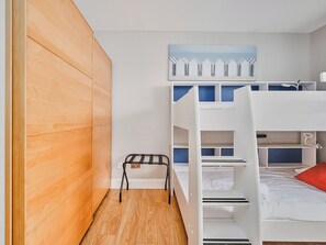 A bunk bed room with a wooden wardrobe, a small table, and a painting on the wall. - No.6 Dunluce Park Apartments - UK52047 (Portrush)