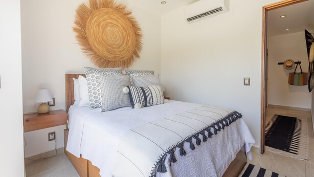 A bedroom with a bed, bedside table, lamp, and a woven wall hanging. - Deluxe 2BD corner unit & Rooftop Pool in Versalles 2BD Condo for rent in Versall (Puerto Vallarta)