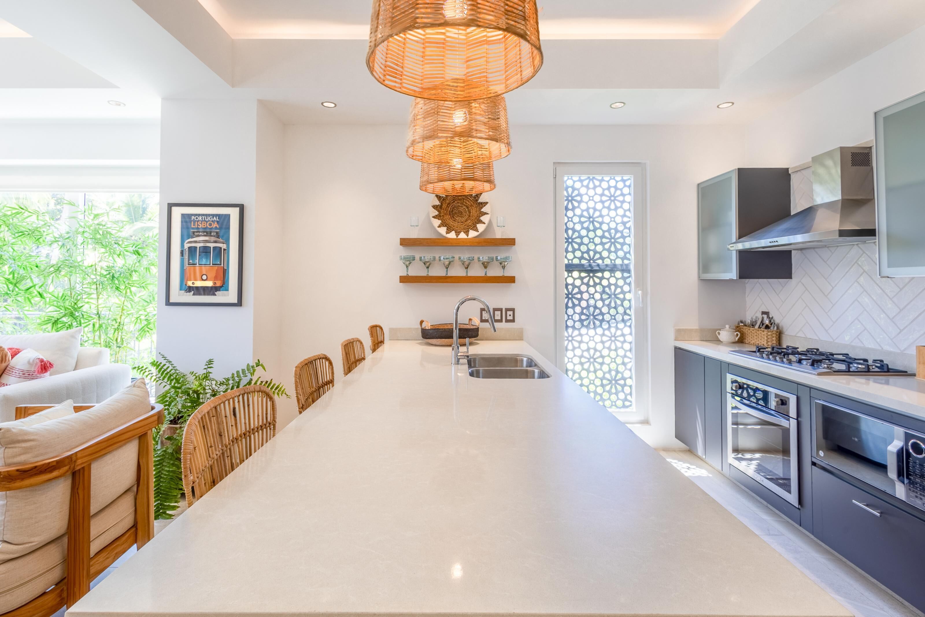 A modern kitchen with a central island, built-in appliances, and a dining area with wicker chairs.
