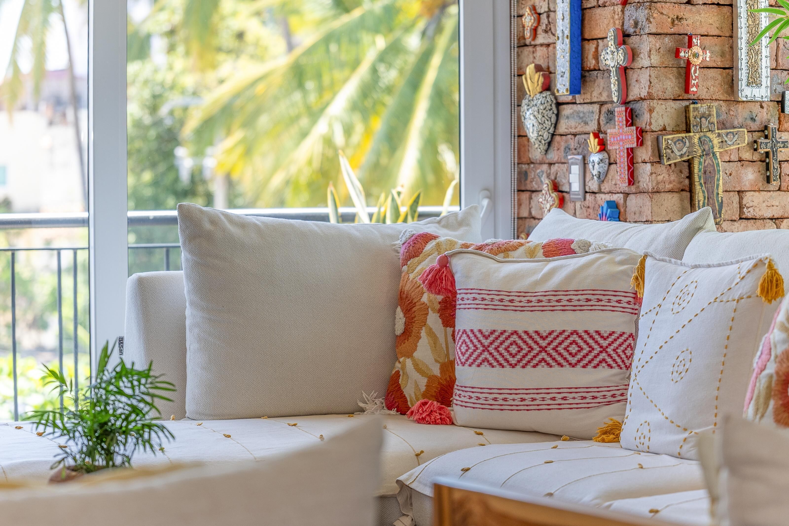 A cozy seating area with a sofa and cushions, a small plant, and a brick wall with various decorations.