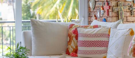 A cozy seating area with a sofa and cushions, a small plant, and a brick wall with various decorations.