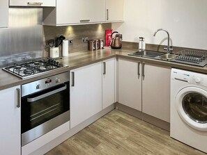 A modern kitchen with stainless steel appliances, a built-in oven, a dishwasher, and a sink with a drying rack. - 2 bedroom accommodation in Cellardyke (Cellardyke)
