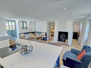 A modern kitchen with a marble countertop, a dining area with a wooden table, and a cozy seating area with a blue sofa. - 5 bedroom accommodation in Redford (Redford)
