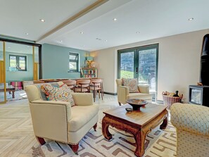 A spacious living room with a fireplace, a dining area, and a large window providing natural light. - 5 bedroom accommodation in Redford (Redford)