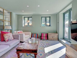 A living room with a sofa, a coffee table, and a television. There are windows and a door visible. - 5 bedroom accommodation in Redford (Redford)