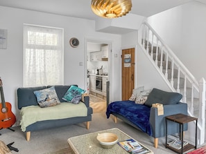 Ein Wohnzimmer mit zwei Sofas, einem Couchtisch, einer Gitarre und einer Treppe.