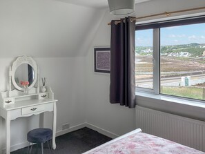 A bedroom with a bed, a vanity with a mirror, a window with a view of a landscape, and a radiator.
