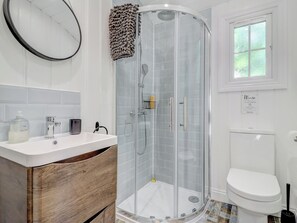 Ein modernes Badezimmer mit einer gläsernen Duschkabine, einem weißen Waschbecken und einer Toilette.