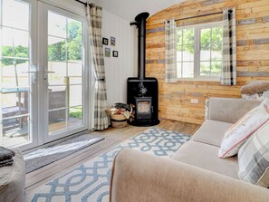Um quarto aconchegante com sofá, lareira, janela com cortinas e vista para o exterior.