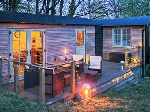 Eine Holzhütte mit Veranda, Sitzgelegenheit im Freien und Lichterketten.
