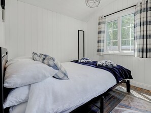 A bedroom with a bed, pillows, a window with curtains, and a wooden floor. - 2 bedroom accommodation in Whitwell (Whitwell)