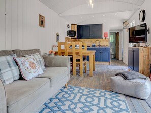 Uma sala de estar acolhedora com um sofá, uma mesa de jantar e uma cozinha equipada com micro-ondas e armários.