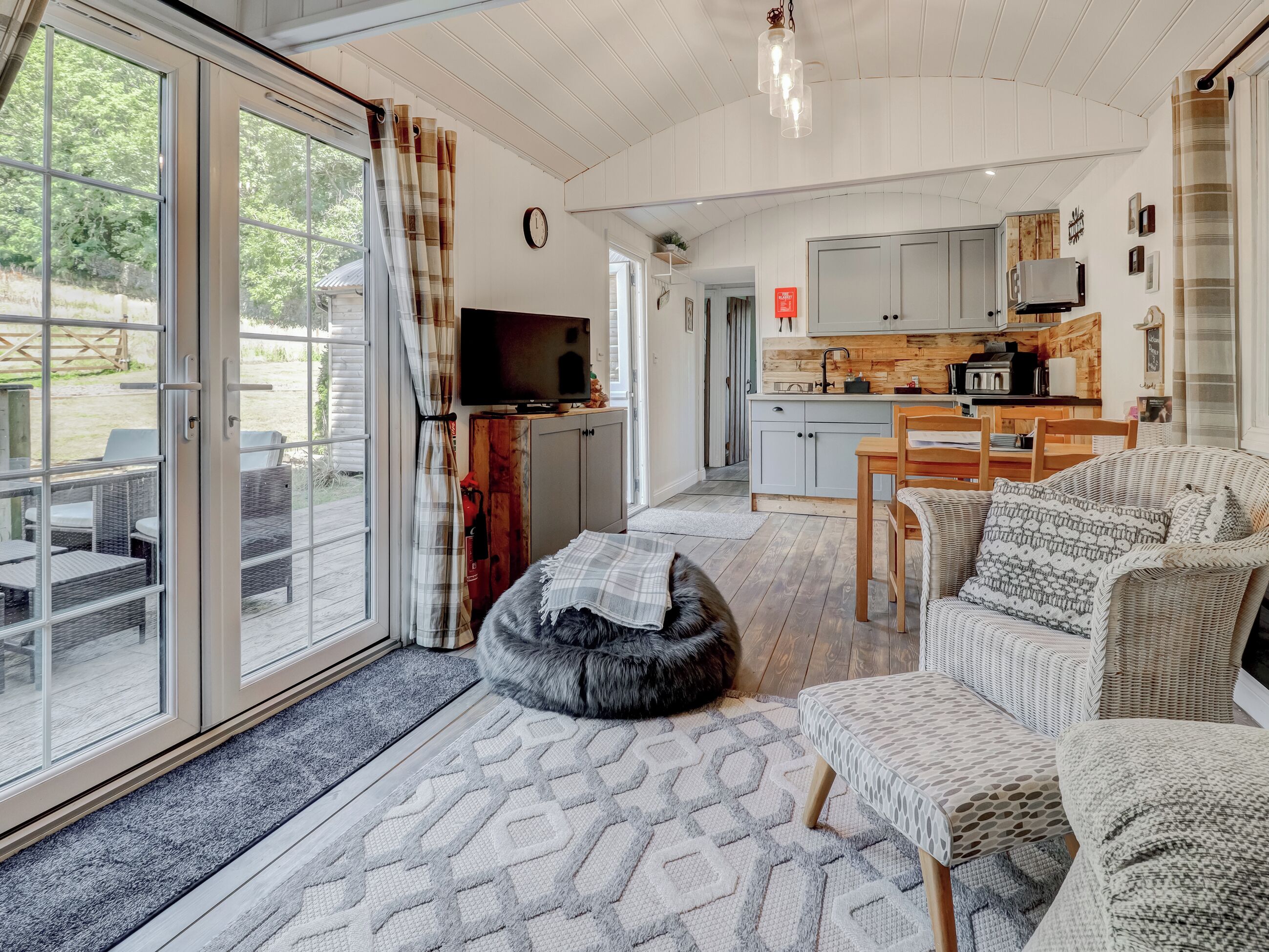 A spacious living area with a large sliding glass door leading to an outdoor patio, a cozy seating area with a rug, and a kitchen with modern appliances.