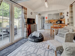 A spacious living area with a large sliding glass door leading to an outdoor patio, a cozy seating area with a rug, and a kitchen with modern appliances. - 2 bedroom accommodation in Whitwell (Whitwell)