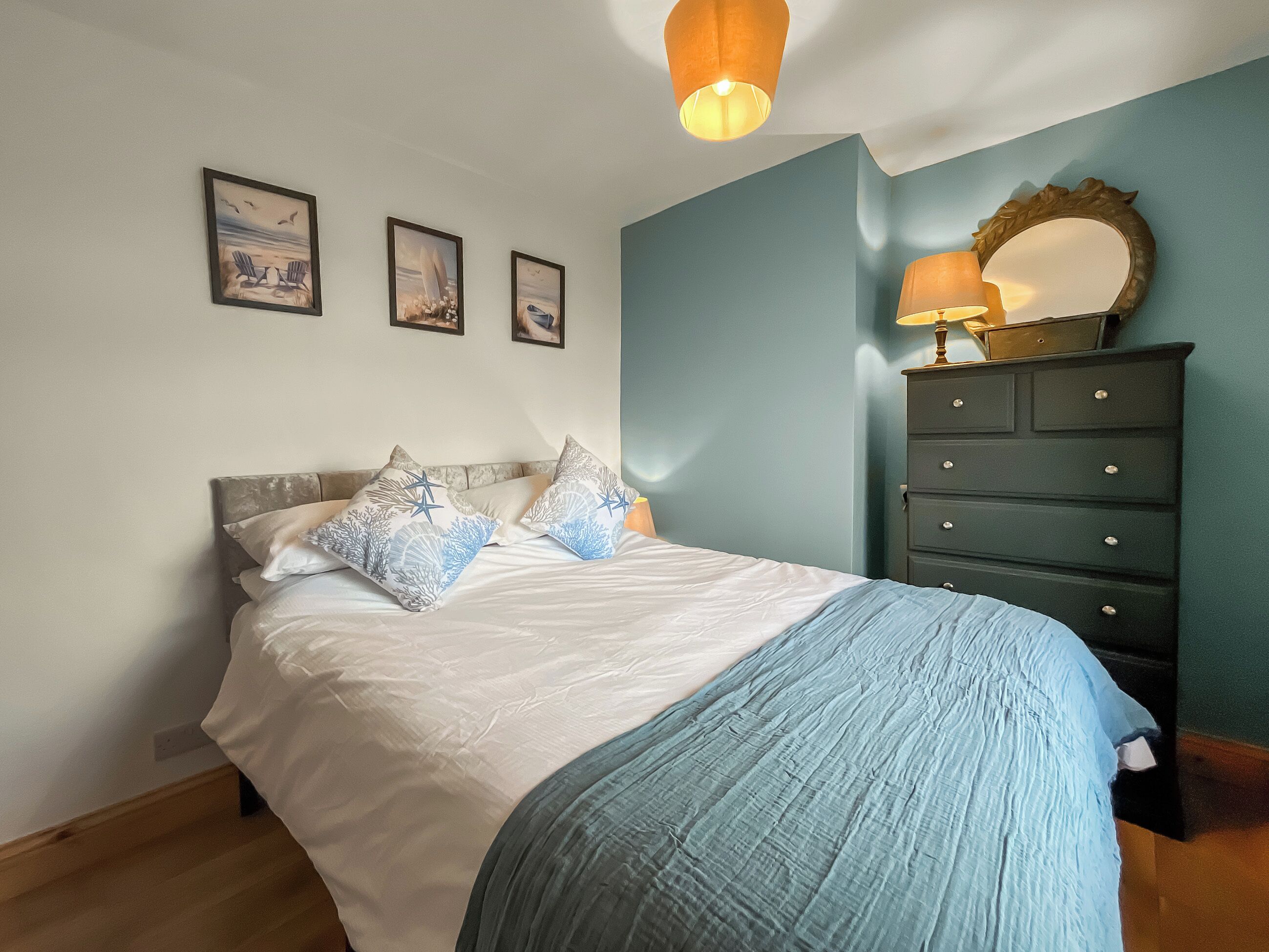 Une chambre à coucher avec un lit, une commode et des œuvres d’art murales.