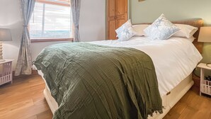 Ein Schlafzimmer mit Bett, Vorhängen, einem Holzschrank und Wandbildern.