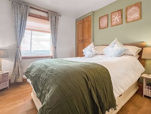 Una camera da letto con un letto, tende, un armadio in legno e decorazioni alle pareti.